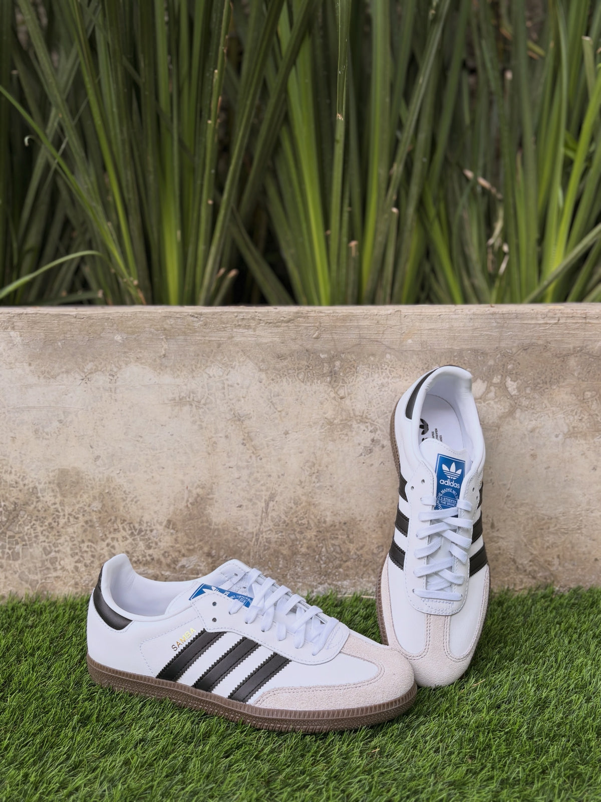 Tenis 𝐋𝐔𝐀𝐋 Adidas Samba blancos de piel con franjas negras, puntera de ante y suela de goma color caramelo.