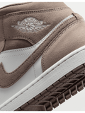 Zapatillas Air Jordan 1 Mid SE de gamuza y cuero en taupe y blanco con logo Wings y Swoosh.