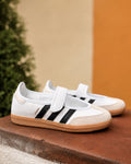 Tenis adidas Samba Mary Jane de 𝐋𝐔𝐀𝐋 en color blanco con franjas negras, puntera de ante y suela de goma caramelo.