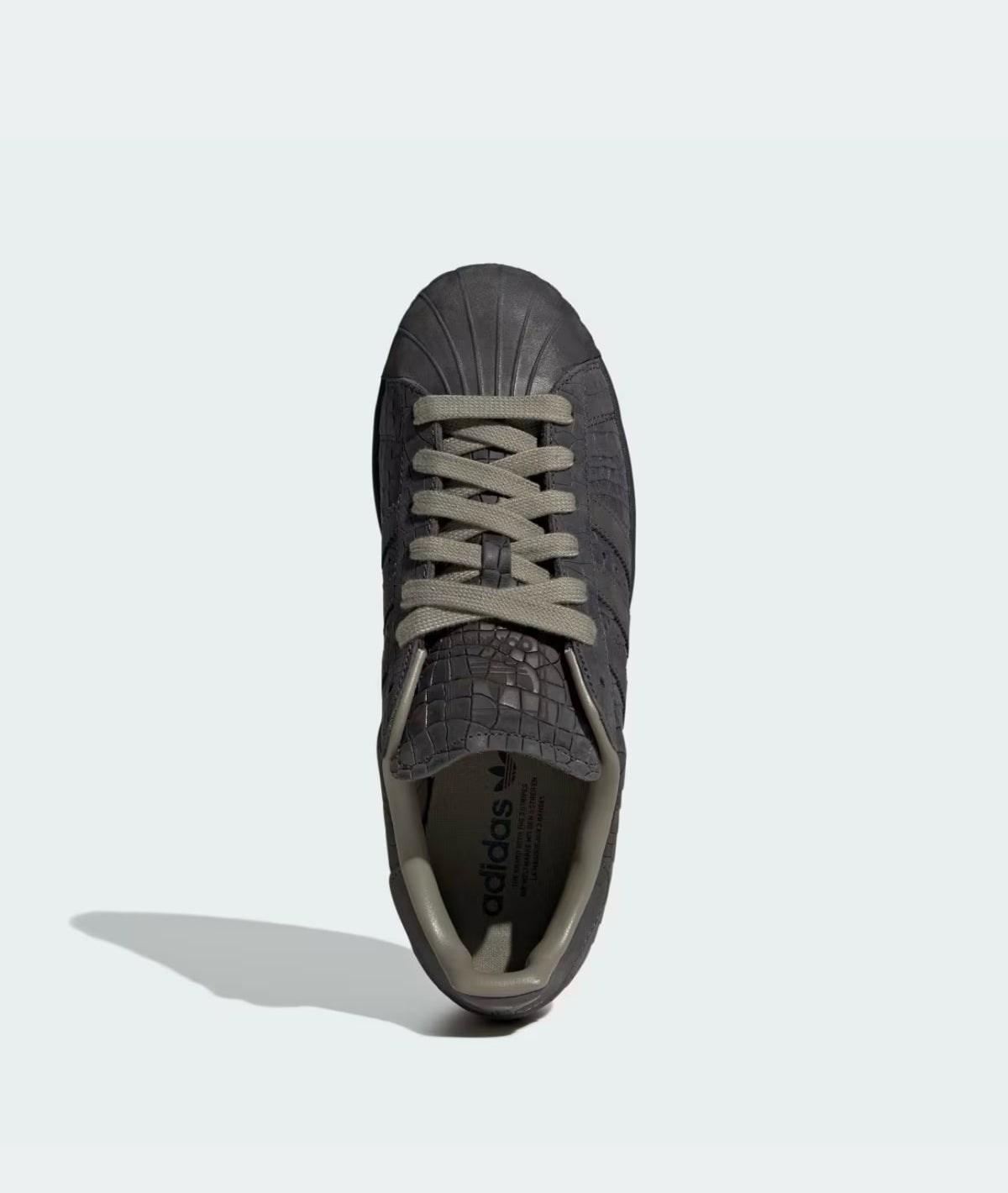 Tenis adidas Superstar 𝐋𝐔𝐀𝐋 en color gris oscuro con textura de piel de cocodrilo y punta de concha clásica.